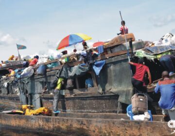 Rescue teams searching the Congo River after a deadly boat capsizing incident; smoke and debris visible in the background.
