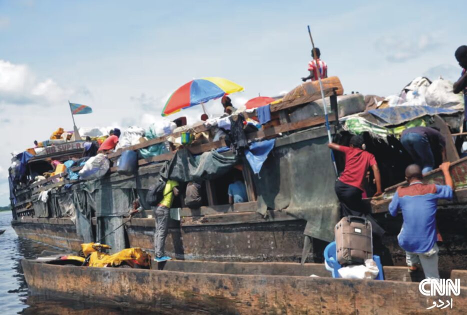 Rescue teams searching the Congo River after a deadly boat capsizing incident; smoke and debris visible in the background.