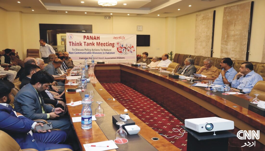 A group of health professionals and policymakers seated at a conference table, reviewing documents during a serious discussion on ultra-processed foods and NCDs.