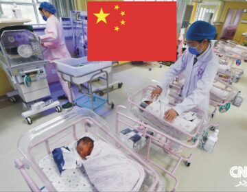 A pregnant woman in a hospital bed receiving an epidural from a doctor, with medical staff assisting in the background.