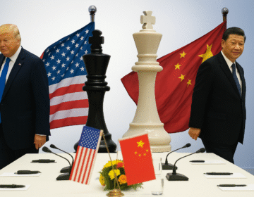Former U.S. President Donald Trump speaking at a podium with U.S. and Chinese flags in the background.